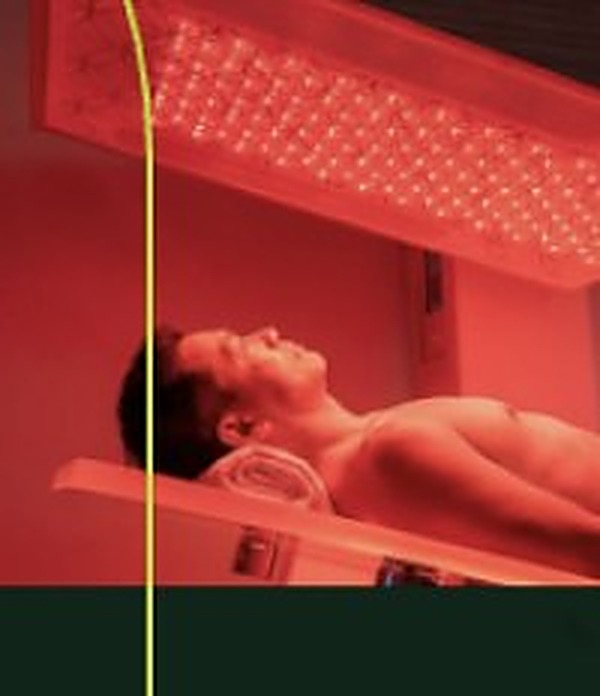 Person lying under red light therapy